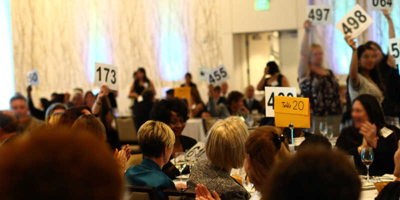 Pictures of people bidding on items at an auction